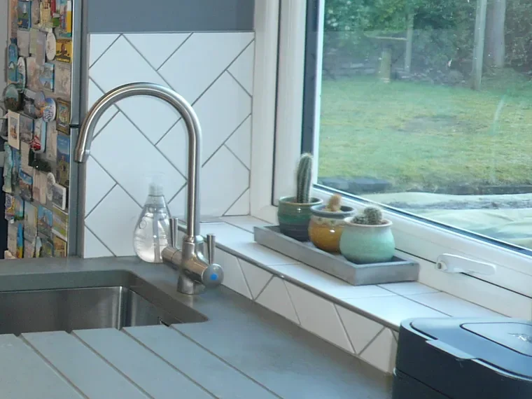 Grey solid surface kitchen worktop with drainer grooves routed beside an undermounted sink, under a window in a Clydebank kitchen