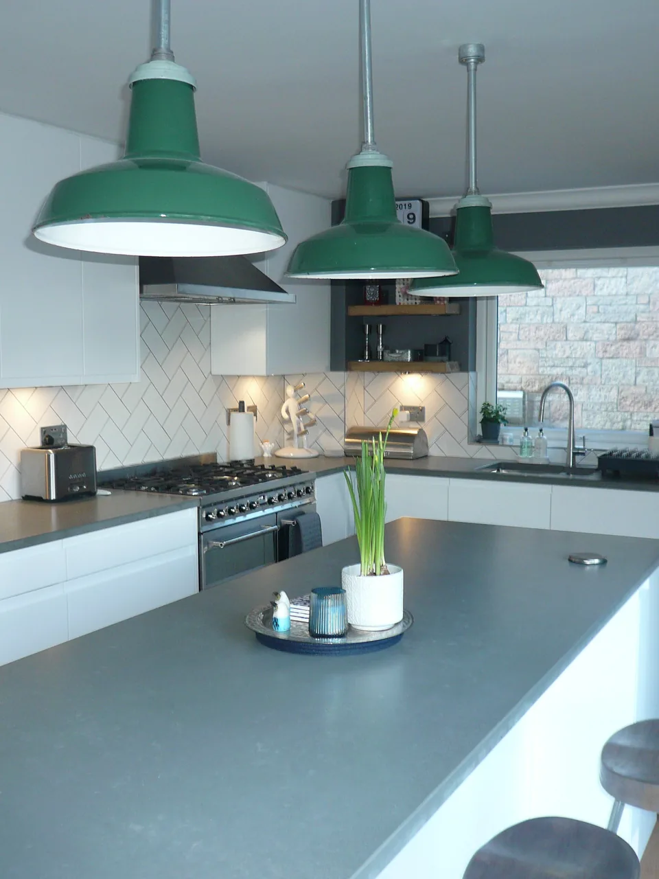 Matt white handleless kitchen with a grey worktop island and green enamel pendants, Clydebank