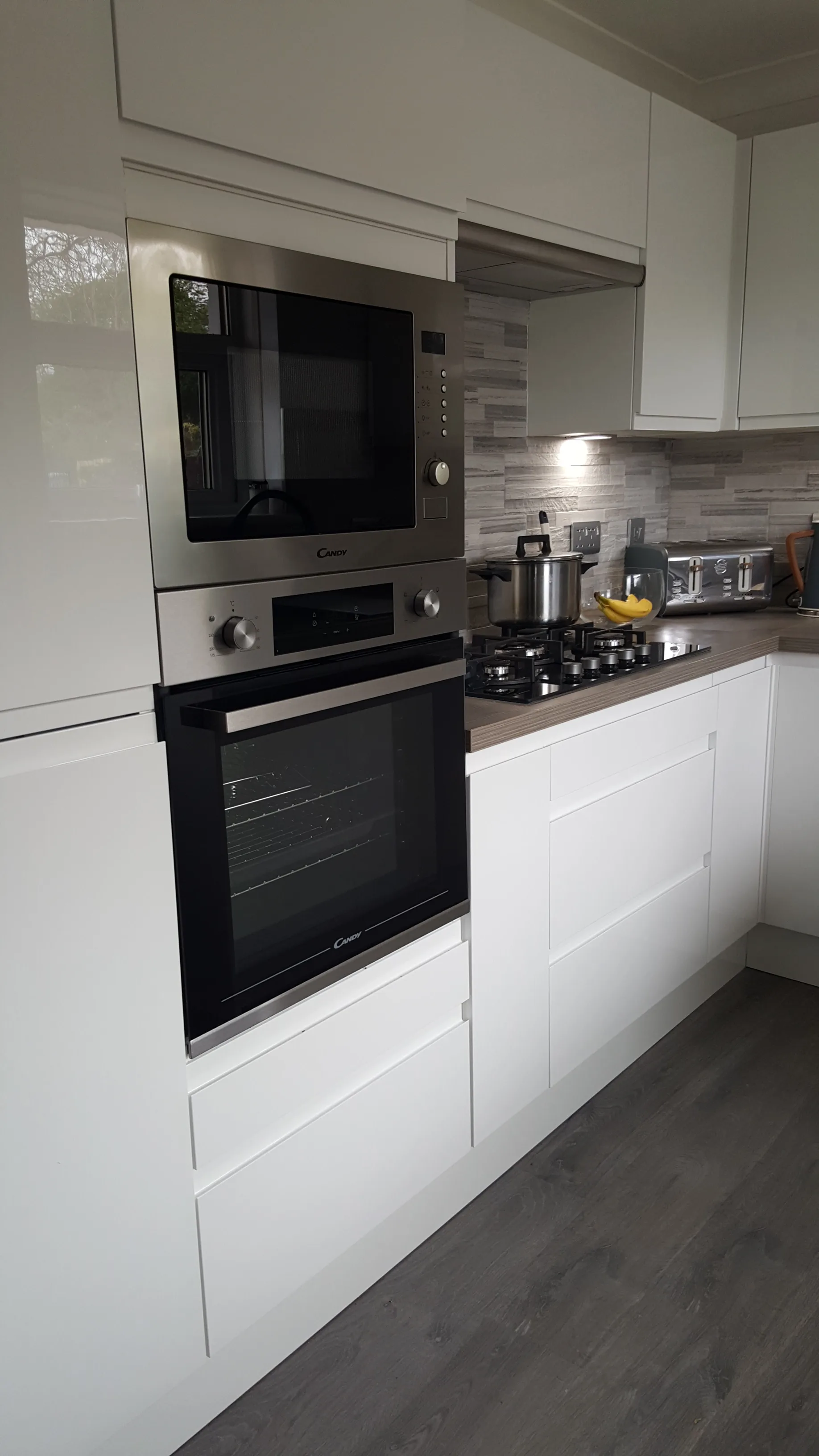 Full-height view of the raised oven housing in the white gloss handleless kitchen