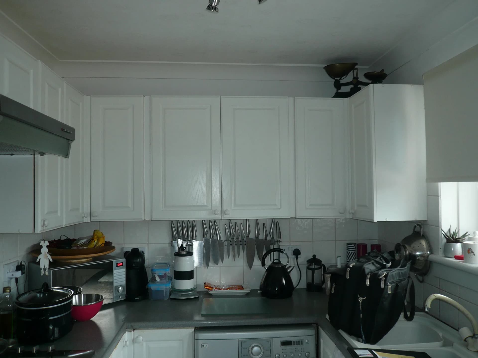 The old kitchen before renovation, with raised-panel white doors and a crowded worktop