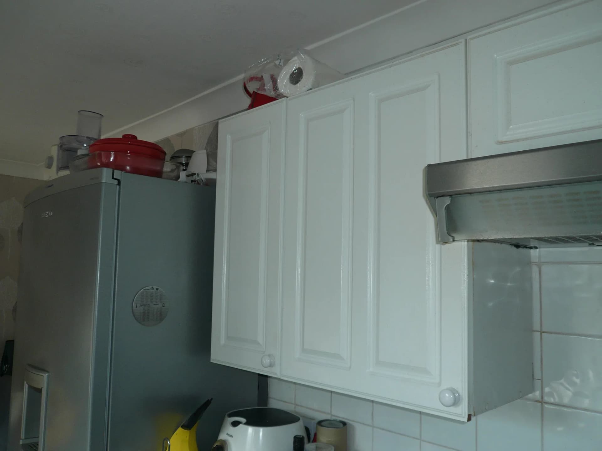 Old wall cupboards and cooker hood beside the fridge freezer before the renovation