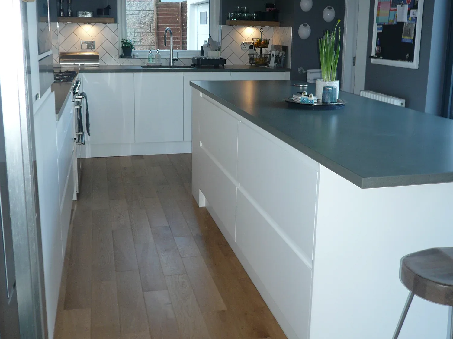 Slate grey solid surface worktop running the length of a white handleless kitchen island in a Clydebank kitchen