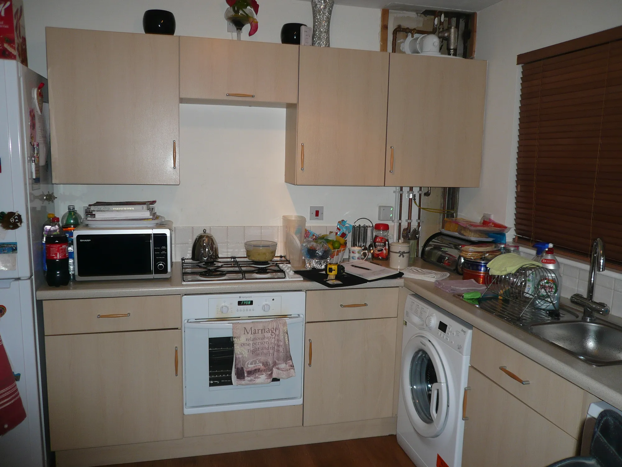 The old maple-effect kitchen before renovation, with appliances squeezed along one wall