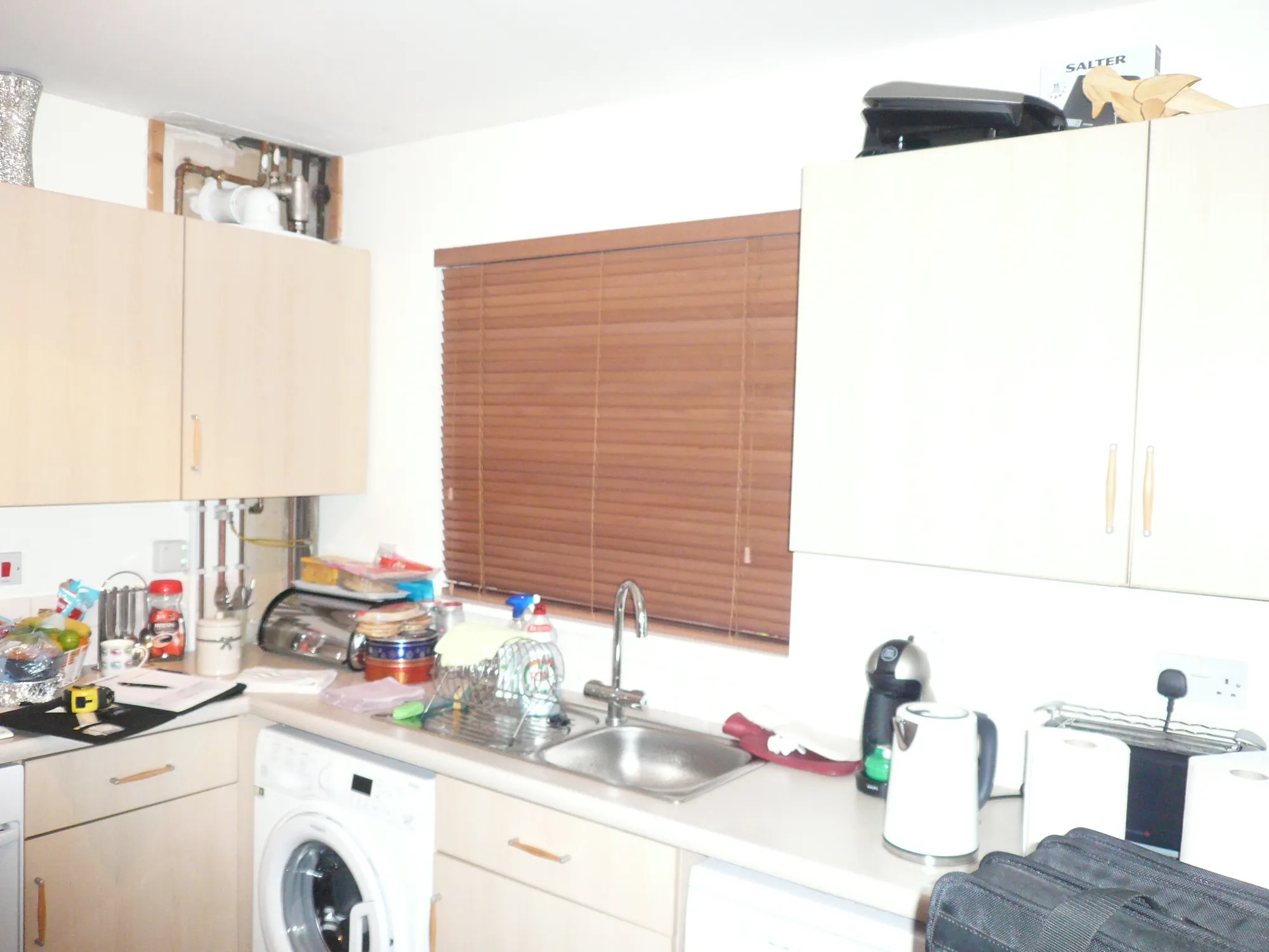 Exposed boiler pipework above the old kitchen units before the renovation