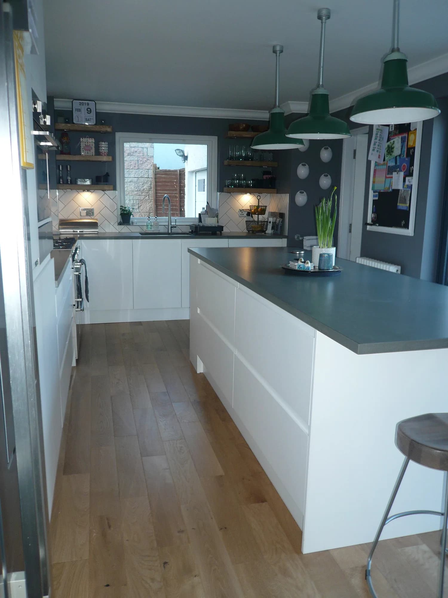 Kitchen island with wide handleless drawers and an open bookshelf end, looking towards the sink run