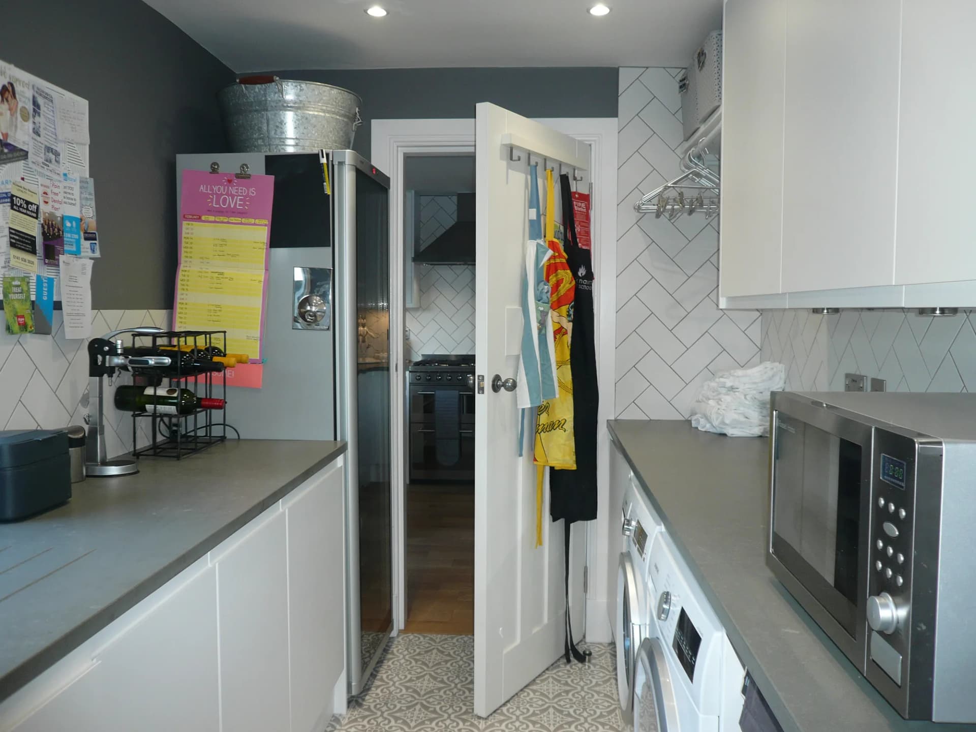 Utility room fitted with the same white handleless doors and grey worktops as the kitchen