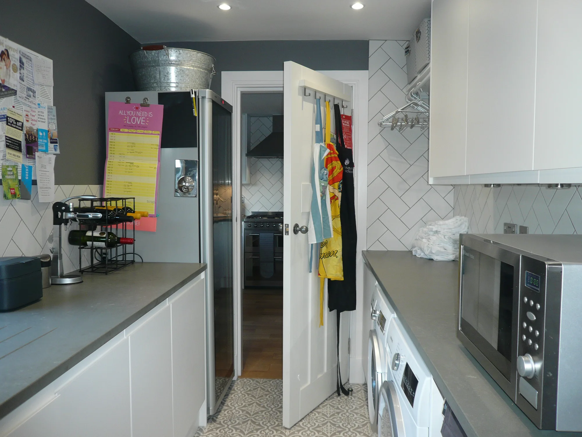 Utility room fitted with the same white handleless doors and grey worktops as the kitchen