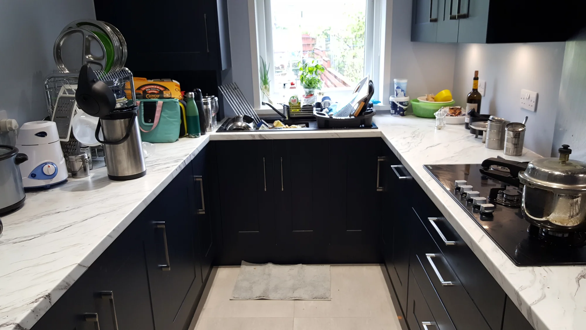 U-shaped indigo kitchen in Glasgow, photographed in use with the sink below the window