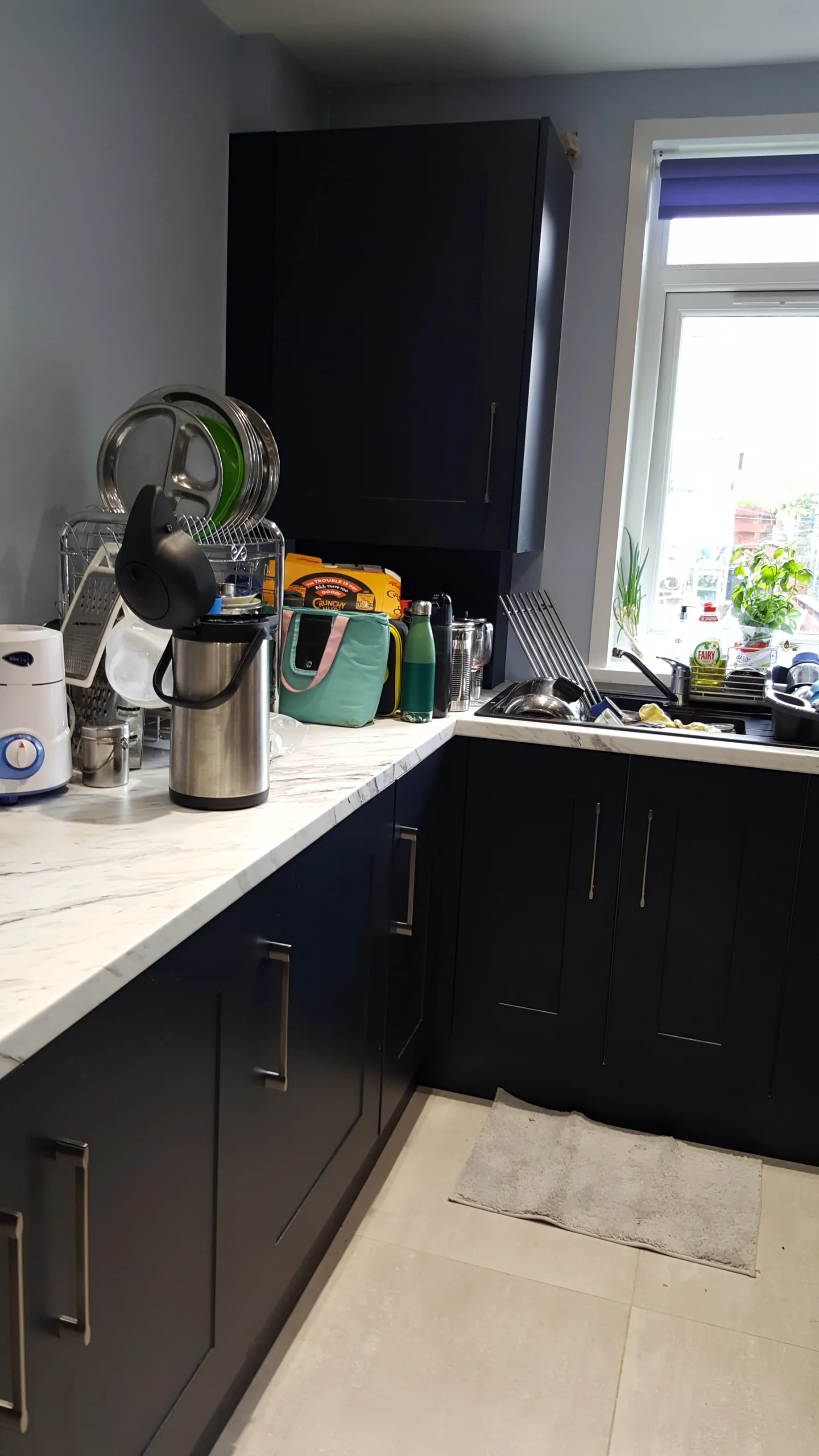 Sink run below the window in the indigo Oxford kitchen, with deep drawers and slim steel handles