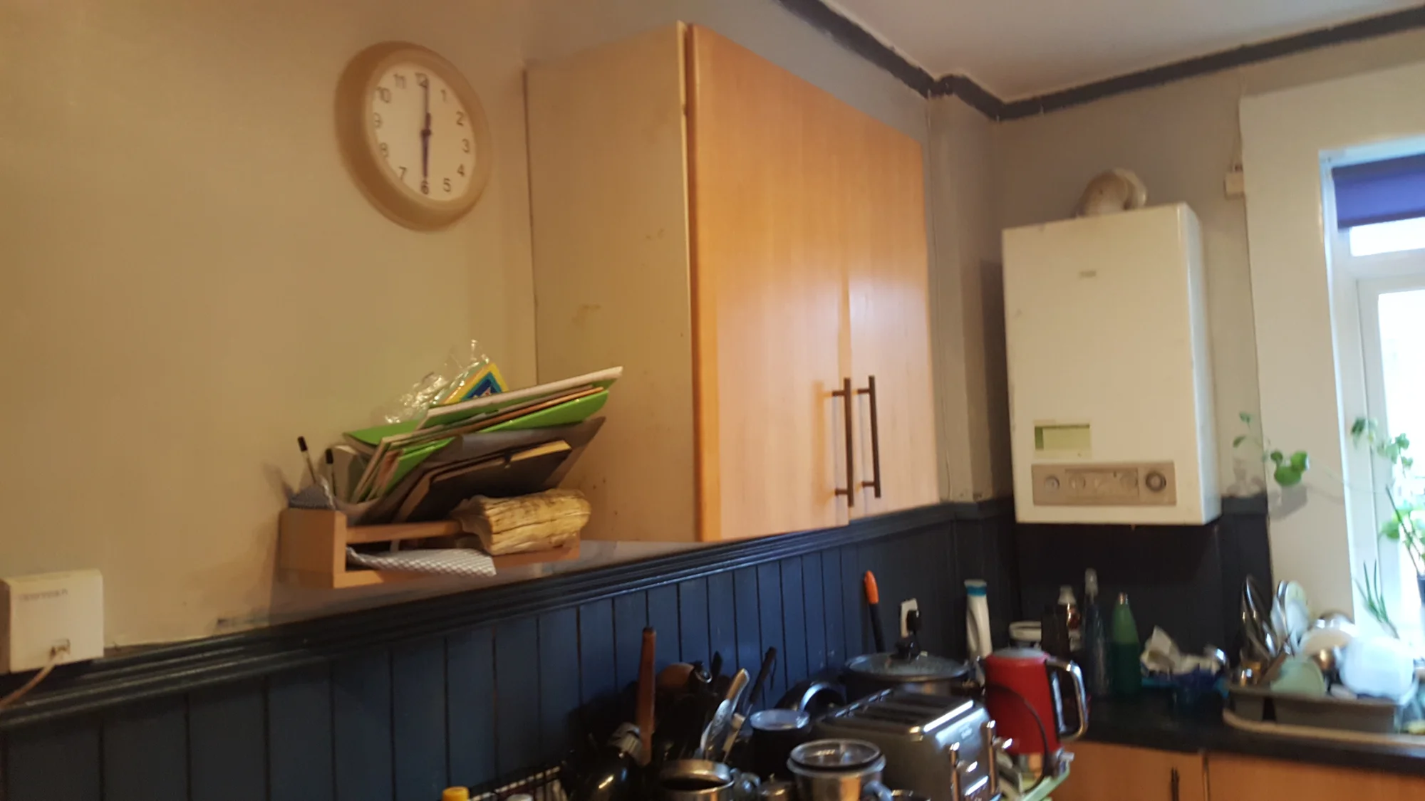 The old kitchen before renovation, with beech-effect wall units and the boiler mounted in open view